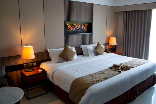 A neatly made bed in a modern bedroom with two bedside lamps, three pillows, and a wall-mounted decorative feature above the headboard, ending the sentence.