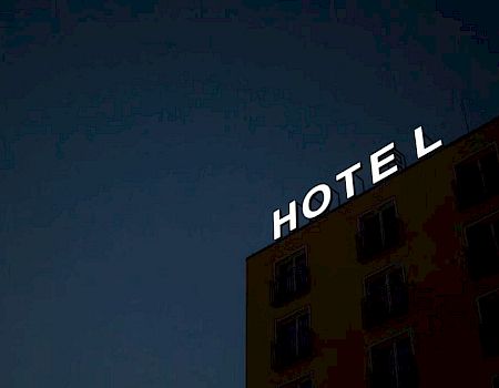 The image shows a building in the evening with a lit sign reading 